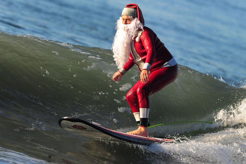 Père Noël qui surf une vague